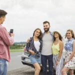 East Coast Family Vacations: man-taking-picture-his-friends-standing-front-car-road