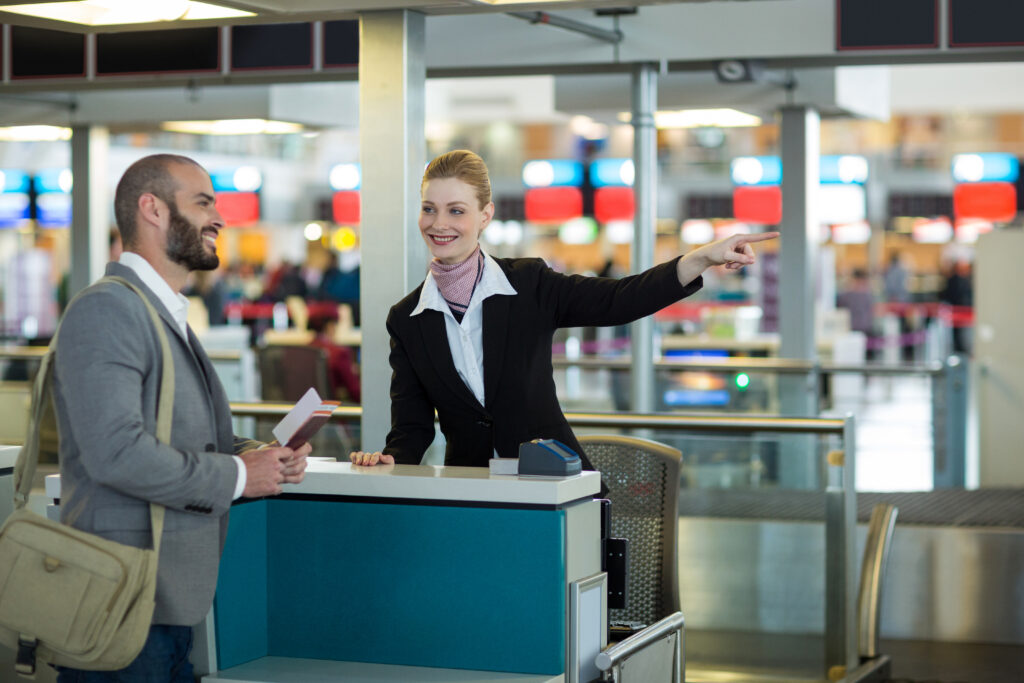 Chicago to Vegas flight time: Airline check-in attendant showing direction to commuter at check-in counter in airport terminal