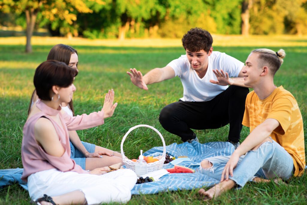 fun things to do with teenagers: Group of friends having fun at a picnic blanket with goodies, in a park during the pandemic in Chisinau, Moldova