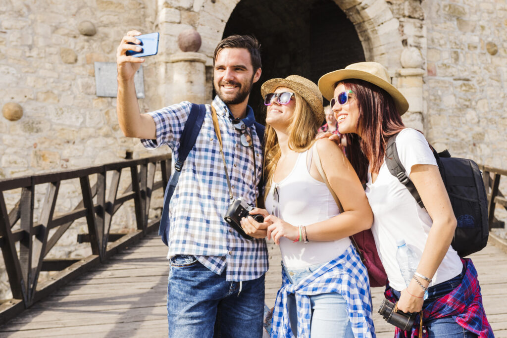 safe travels in Italian: smiling-young-friends-taking-selfie-cellphone